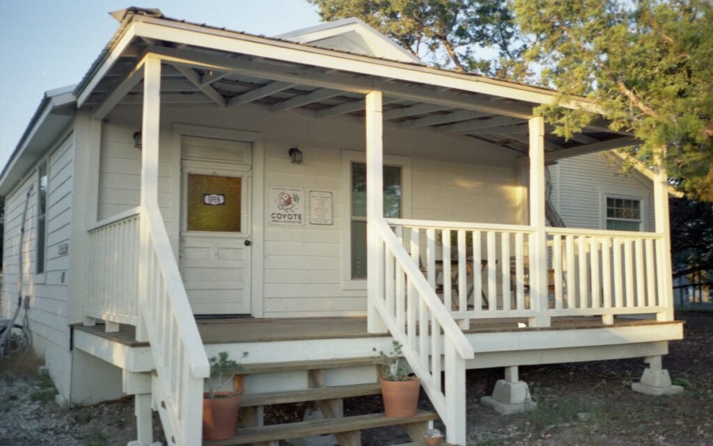 A photo of a white, wooden house with a front porch where Coyote Herbs and Acupuncture is located